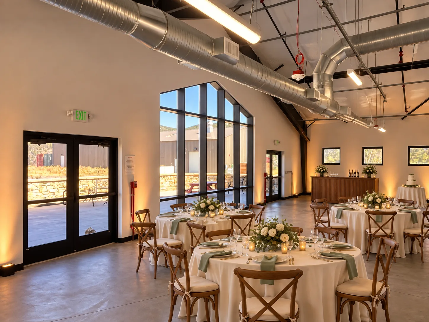 Round reception tables beside tall windows in the event room